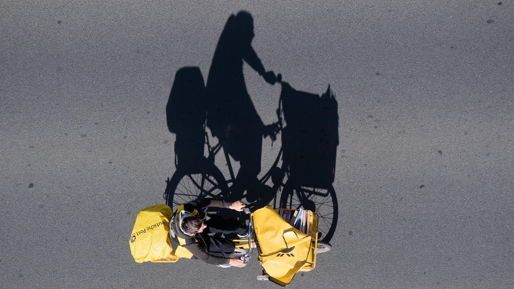 14.05.2018, Niedersachsen, Braunschweig: Ein Postbote auf einem Fahrrad wirft einen langen Schatten auf eine Straße - fotografiert aus der Vogelperspektive vom Braunschweiger Rathausturm. Foto: Julian Stratenschulte/dpa +++ dpa-Bildfunk +++