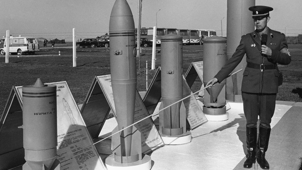 Dieses Archivbild zeigt einen sowjetischen Soldaten, der Munition präsentiert, in dem sich chemische Giftstoffe befinden, während Diplomaten und Journalisten aus dem Westen eine Anlage in Schichany besuchen.
