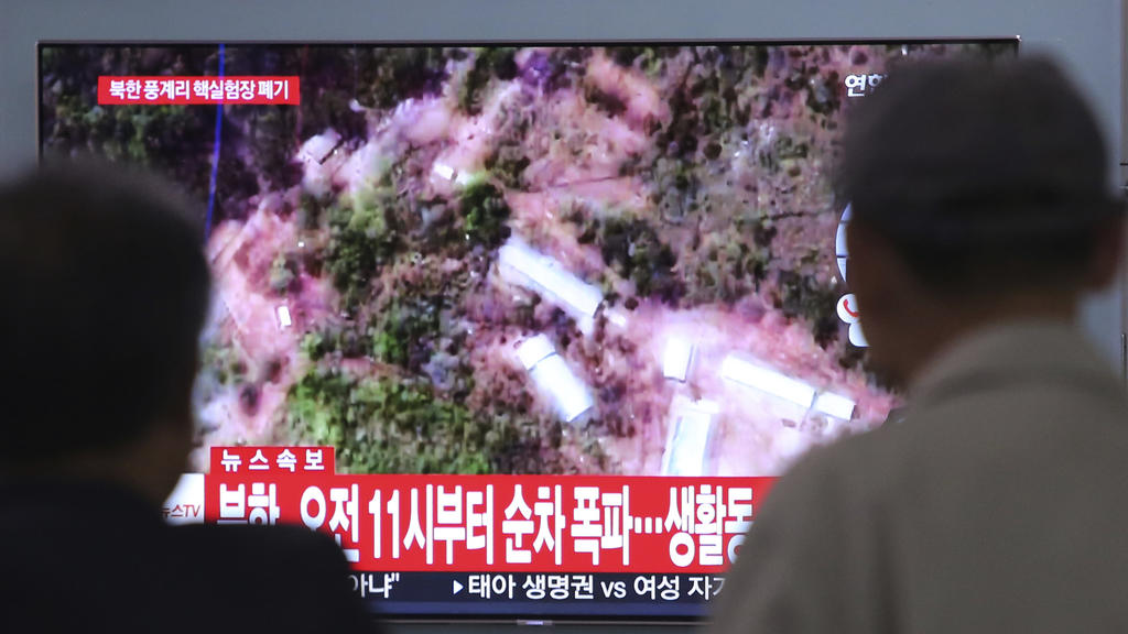 24.05.2018, Südkorea, Seoul: Menschen verfolgen am Bahnhof von Seoul eine Nachrichtensendung auf einem Fernseher, die Satellitenbilder von dem Atomtestgelände Punggye-ri in Nordkorea zeigt. Nordkorea hat nach Medienberichten sein umstrittenes Atomtes